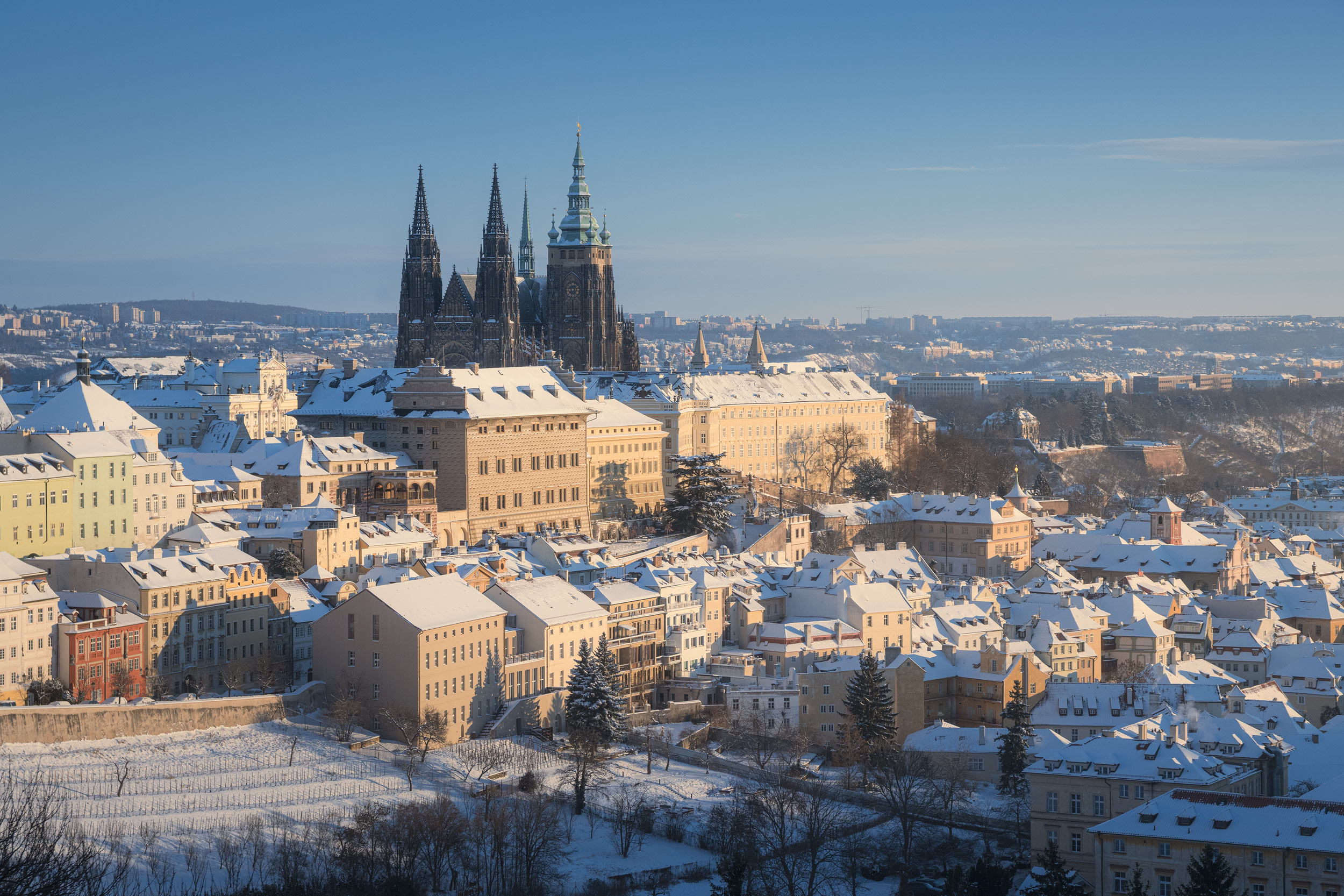 Prague Castle above snow-covered rooftops in clear winter light